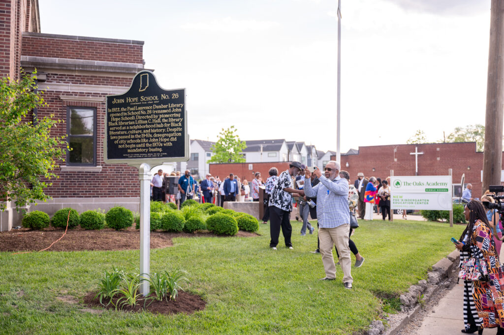 A School 26 alum stands in front of the newly unveiled historical marker honoring John Hope School 26 and the Paul Laurence Dunbar Library