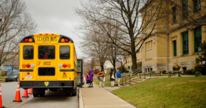 A school bus is being loaded in front of a school